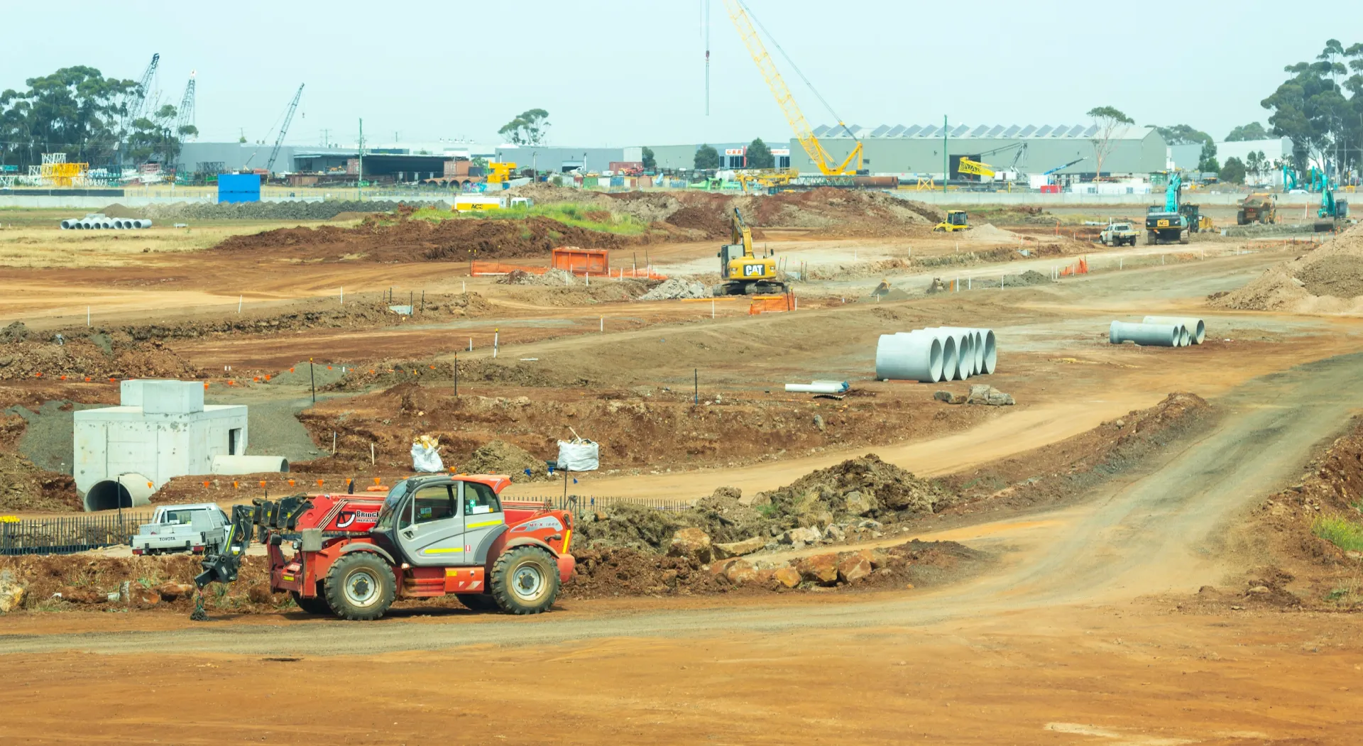 Underground utilities jobsite with graded roadbed and concrete pipes staged for installation